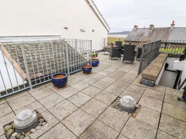 A rooftop terrace with patio furniture and empty planters at Westmorland Cottage in Grange-Over-Sands