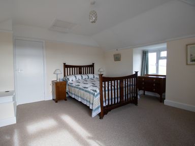 A bedroom with a wooden bed and chest of drawers by a window at Thorncroft West Bay