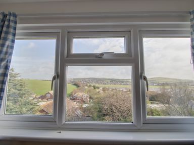A view through a window showing houses trees and green hills at Thorncroft in West Bay