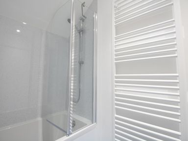 A bathroom with a bathtub shower and a white towel radiator at Thorncroft in West Bay