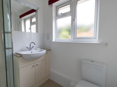 A bathroom with a sink cabinet a toilet and a frosted window at Thorncroft West Bay