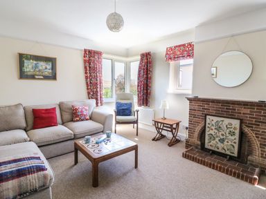 A living room with beige sofa and red pillows coffee table and fireplace at Thorncroft in West Bay