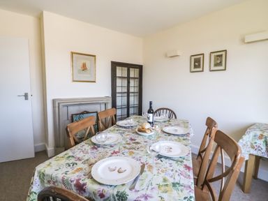 A dining room with a table set for five with plates glasses and bread at Thorncroft in West Bay