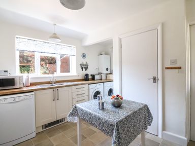A kitchen with a table covered with a cloth and kitchen appliances at Thorncroft in West Bay