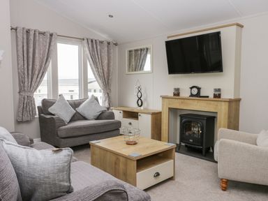 A living room with sofas a coffee table a fireplace and a mounted television at Cayton Pines Cayton Bay near Scarborough