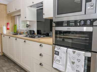 A kitchen with white cabinets a gas stove a microwave oven and a built in oven at Cayton Pines Cayton Bay near Scarborough