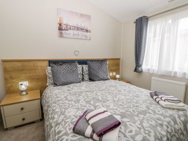 A bedroom with a double bed two bedside tables with lamps a window with curtains and a New York City picture at Cayton Pines Cayton Bay near Scarborough