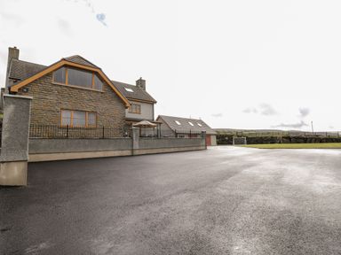 A house with stone and grey walls a paved driveway and a small soccer goal in a field at Grooms Quarters at Pant y Gaseg Farm in Ammanford