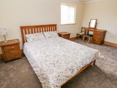 A bedroom with a double bed bedside tables a dressing table and two chairs at Grooms Quarters at Pant y Gaseg Farm Ammanford
