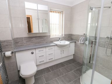 A bathroom with a toilet sink shower and storage cabinets at Grooms Quarters at Pant y Gaseg Farm in Ammanford