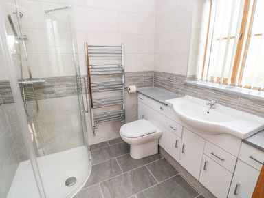 A bathroom with a shower, toilet, sink, and storage cabinets at Grooms Quarters at Pant y Gaseg Farm in Ammanford