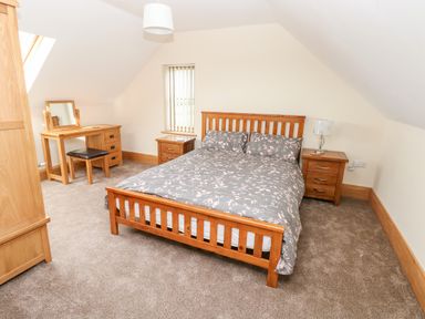 A bedroom with a double bed two bedside tables a dressing table and a wardrobe at Grooms Quarters at Pant y Gaseg Farm in Ammanford