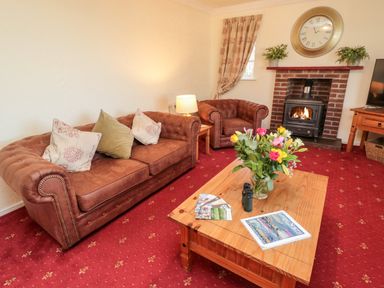 A living room with brown leather sofas a wooden coffee table a fireplace and a television at Coquet View Cottage in Rothbury
