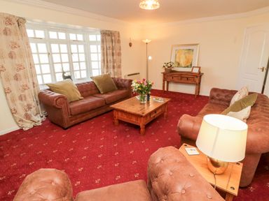 A living room with brown sofas a wooden coffee table and a side table with a lamp at Coquet View Cottage in Rothbury