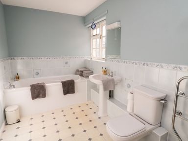 A bathroom with a bathtub, sink, toilet, towels, and a window at Coquet View Cottage in Rothbury