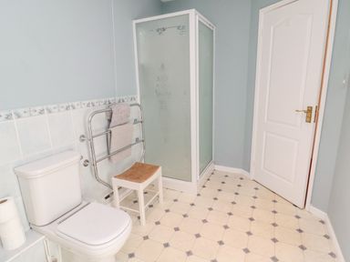 A bathroom with a toilet towel rack shower unit and chair at Coquet View Cottage in Rothbury