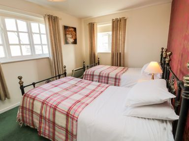 A bedroom with two single beds with plaid blankets and a lamp on the bedside table at Coquet View Cottage in Rothbury