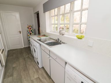 A laundry room with a sink washing machine dishwasher and ironing board at Coquet View Cottage in Rothbury