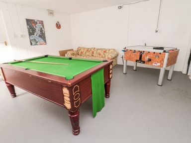 A games room with a pool table, foosball table, floral sofa, and a space-themed wall poster at Coquet View Cottage in Rothbury