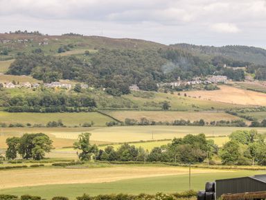 A countryside landscape with fields trees and houses in the distance at The Steadings in Rothbury