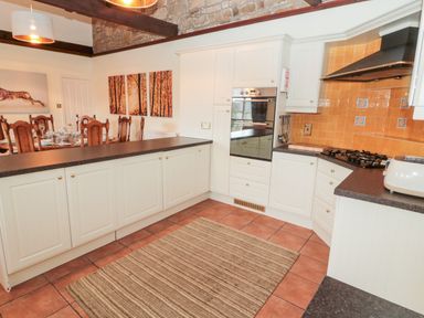 A kitchen with white cabinets an oven a gas stove and a brown countertop at The Steadings in Rothbury