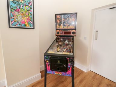 A pinball machine with kiss theme in a corner of a room with wooden floor and framed artwork on the wall at The Steadings in Rothbury