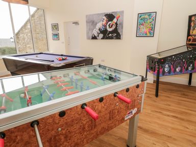 A game room with a foosball table pool table and pinball machine at The Steadings in Rothbury