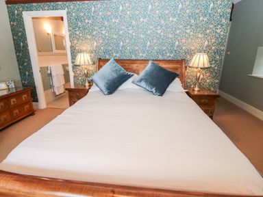 A bedroom with a bed and two pillows two bedside tables with lamps and a dresser at The Steadings in Rothbury