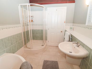 A bathroom with a shower cubicle a sink and a bathtub with towels at The Steadings in Rothbury