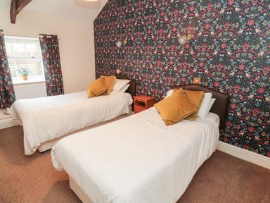 A bedroom with two single beds and floral wallpaper at The Steadings in Rothbury