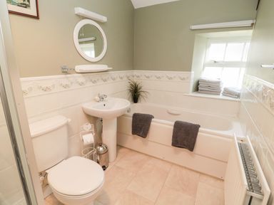 A bathroom with a toilet sink bathtub and towels on a window sill at The Steadings in Rothbury