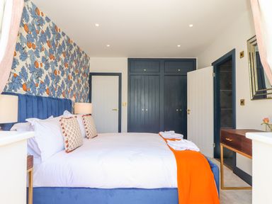 A bedroom with a blue bed and floral wallpaper at See Two Seas Cape Cornwall in St Just
