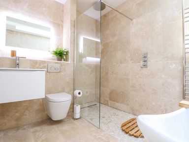 A bathroom with a wall-mounted toilet a glass-enclosed shower and a sink at See Two Seas Cape Cornwall in St Just
