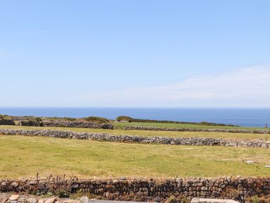 A coastal field with stone walls and the ocean in the background at See Two Seas Cape Cornwall in St Just