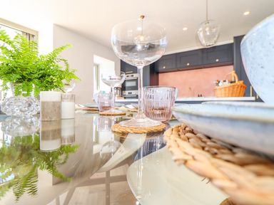 A dining table set with glassware plates and a fern plant in a kitchen at See Two Seas Cape Cornwall in St Just