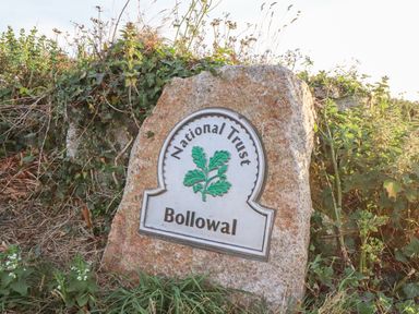 A stone sign for National Trust Bollowal surrounded by grass and plants