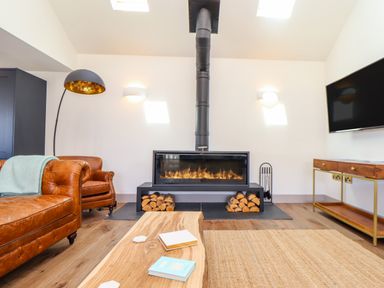A living room with a fireplace a leather sofa a wooden coffee table and a television at See Two Seas Cape Cornwall in St Just