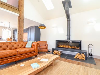 A living room with a leather sofa armchair wood coffee table and a fireplace at See Two Seas Cape Cornwall in St Just
