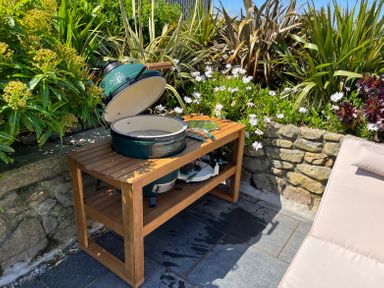A green ceramic grill on a wooden table with garden plants and a stone wall in the background at See Two Seas Cape Cornwall St Just