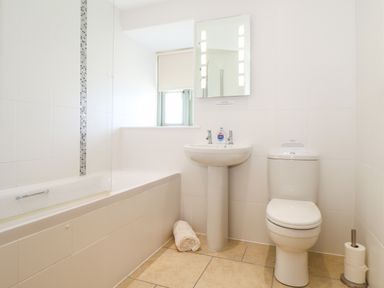 A bathroom with a bathtub a sink mirror and toilet at Pen Tewan in Sennen