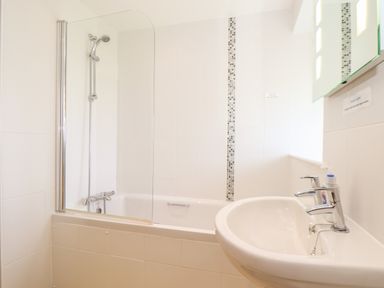 A bathroom with a bathtub shower combination and a sink with a faucet at Pen Tewan in Sennen
