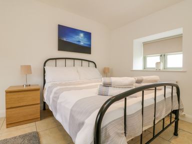 A bedroom with a metal bed frame two bedside tables with lamps and a window at Pen Tewan in Sennen