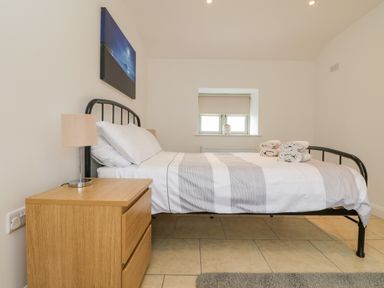 A bedroom with a metal bed frame a wooden bedside table and a window at Pen Tewan in Sennen