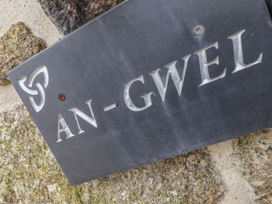 A carved stone house name plaque reading An Gwel mounted on a stone wall at An Gwel in Sennen