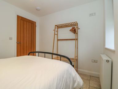 A bedroom with a bed a wooden door a wooden clothes rack with hangers and a radiator at An Garth in Sennen