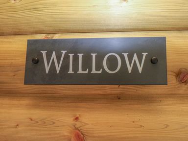 A wooden wall with a metal sign reading Willow at Willow Lodge in St Florence
