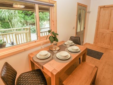 A dining area with a wooden table set for four with plates bowls and glasses at Willow Lodge in St Florence