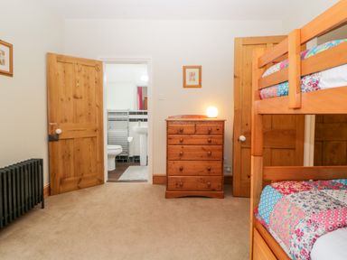 A bedroom with bunk beds a wooden dresser a radiator and a view into a bathroom at Holcombe House in Torquay