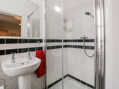 A bathroom with a shower enclosure sink and a red towel at Holcombe House in Torquay