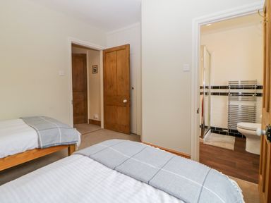 A bedroom with two single beds and gray blankets with a view into a bathroom at Holcombe House in Torquay